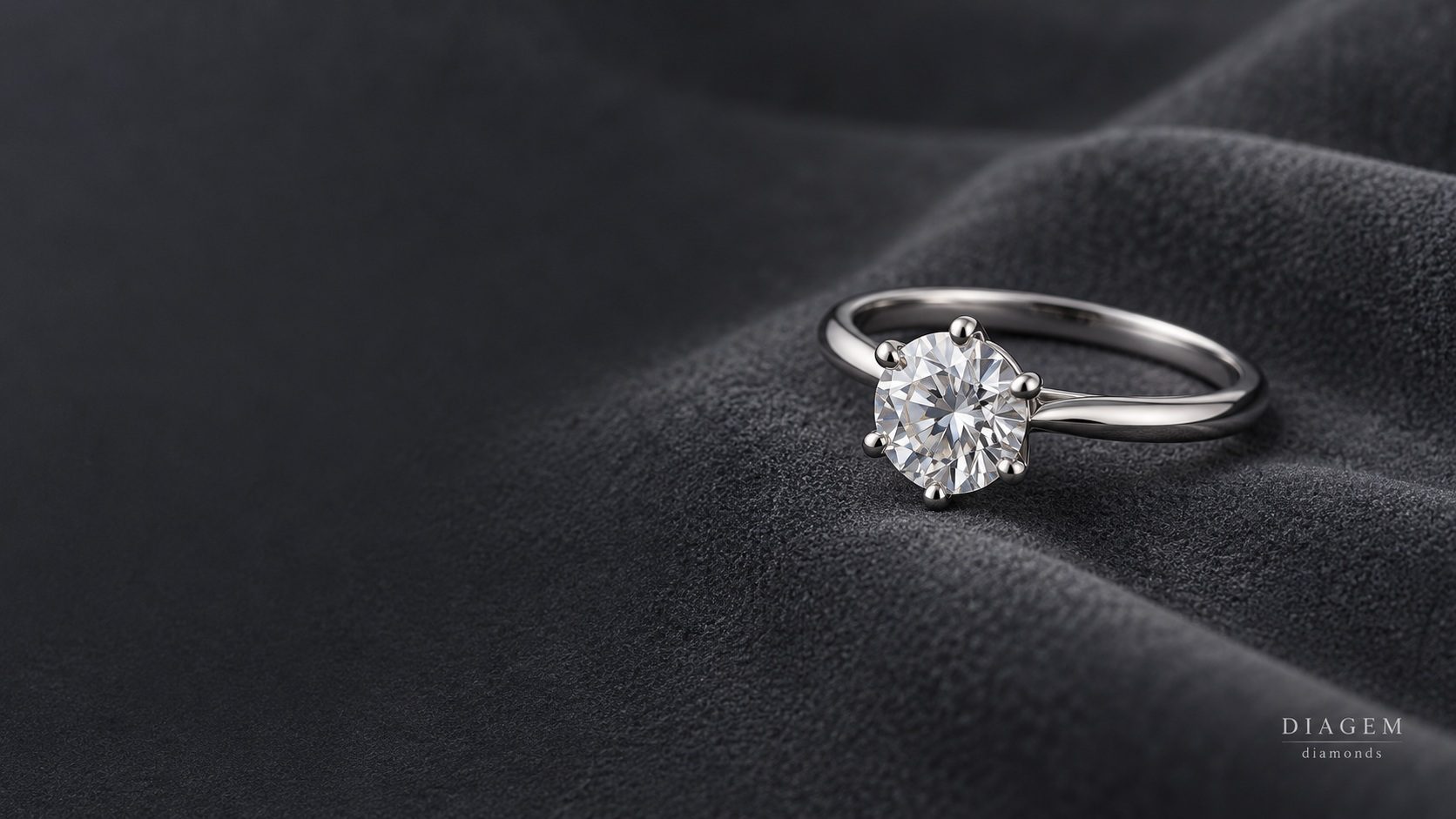 Round diamond solitaire engagement ring on dark velvet
