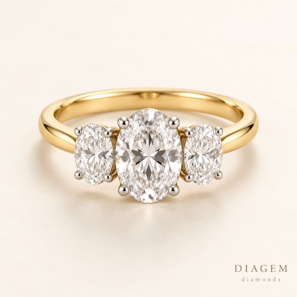 Three-stone engagement ring with oval diamonds and a yellow-gold band